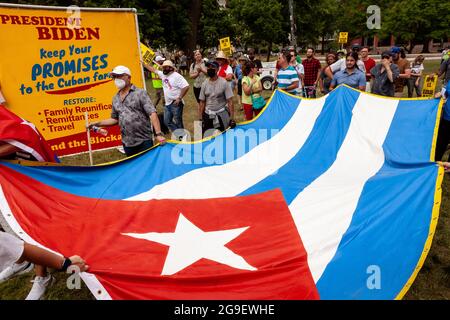 Washington, DC, USA, 25. Juli 2021. Im Bild: Die Demonstranten zeigen eine riesige kubanische Flagge vor einem Schild, das Biden auffordert, die während der Obama-Regierung errichtete Öffnung zwischen den USA und Kuba wiederherzustellen. Die Kundgebung forderte ein Ende der US-Blockade gegen Kuba und feierte die Ankunft von Puentes de Amor (Bridges of Love)-Marschern am Ende ihrer 1300 Meilen langen Reise von Miami nach DC, um gegen die US-Blockade der Insel zu protestieren. Die Demonstranten brachten auch eine Petition mit fast 30,000 Unterschriften, in der Biden aufgefordert wurde, die Blockade zu beenden. Kredit: Allison Bailey / Alamy Live Nachrichten Stockfoto