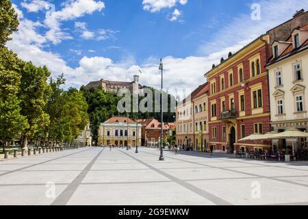 Ljubljana, Slowenien - 15. Juli 2017: Philharmonisches Gebäude auf dem Kongressplatz mit der Burg von Ljubljana im Hintergrund Stockfoto