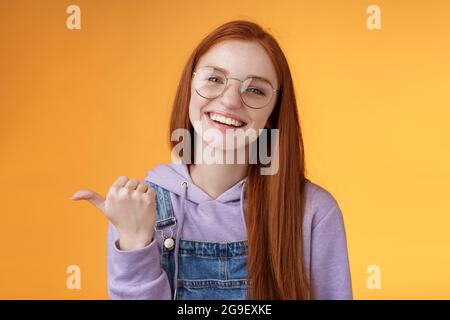 Nette hilfsbereit freundlich aussehende fröhlich europäischen Rotschopf Frau zeigen Daumen links Lächelnd glücklich lachend zeigt, wo finden genial Laden erzählen über Stockfoto