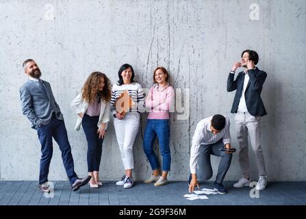 Porträt einer Gruppe von Unternehmern, die im Büro vor einer Betonwand stehen und lachen. Stockfoto