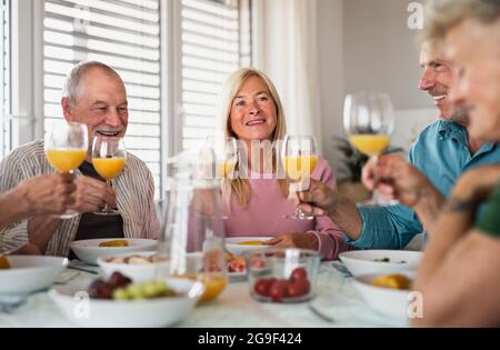 Gruppe älterer Freunde, die in einem Gebäude feiern und beim Essen am Tisch reden. Stockfoto