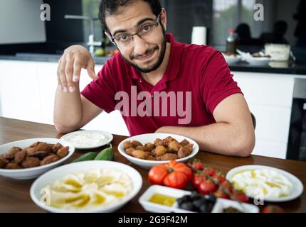 Junger Mann aus dem Nahen Osten, der allein sitzt und traditionelle Speisen isst Stockfoto