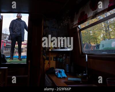 Ein schwarzer Mann, der in Little Venice, London, ein kleines Boot mit einer Deichsel entlang des Regent’s Canal steuert. Stockfoto