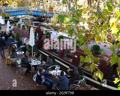 Gäste trinken Kaffee und Erfrischungen vor einem schmalen Bootcafe entlang des Canals der Grand Union in Little Venice Stockfoto