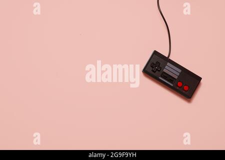 Retro vintage schwarze Spielkonsolen-Controller auf einem pastellrosa Hintergrund mit Kopieplatz und Platz für Text. Stockfoto