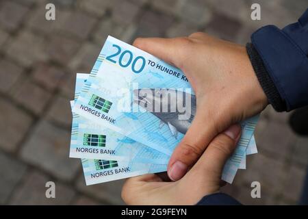 Norwegische Kronen-Banknoten. Hände mit 200 Kronen Papiergeld in Norwegen. Stockfoto