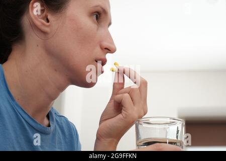 Eine Frau nimmt eine Kapsel Medizin. Konsum der Droge. Behandlung der Krankheit. Stockfoto