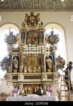 22. Juli 2021, Sachsen, Löbnitz: In der evangelischen Kirche in Löbnitz im nordsächsischen Löbnitz entfernt Tischlermeister Christian Schilling, der auch Mitglied des kirchenrates ist, vorsichtig Staub vom Altar, den Meister Georg Eckhard aus Freiberg 1629 geschnitzt hat. In der Kirche ist eine der größten und am meisten bemalten Bilderbibeln Deutschlands zu sehen. 250 einzelne Tafeln zeigen Motive von Geschichten aus dem Alten und Neuen Testament, musizierende Engel, florale Motive und Porträts von Luther und Melanchton. Die hölzerne Kassettendecke der rund 1000 Jahre alten Kirche wurde 330 bemalt Stockfoto