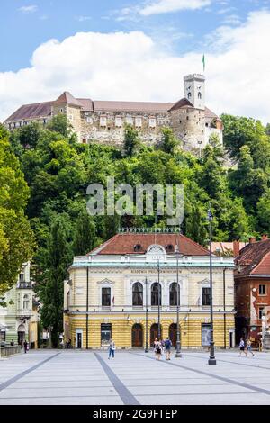 Ljubljana, Slowenien - 15. Juli 2017: Philharmonisches Gebäude auf dem Kongressplatz mit der Burg von Ljubljana im Hintergrund Stockfoto