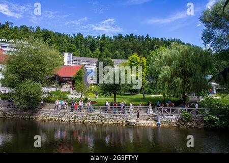 Postojna, Slowenien - 16. Juli 2017: Blick auf Touristen, die durch Postojna mit dem Hotel Jama im Hintergrund wandern Stockfoto