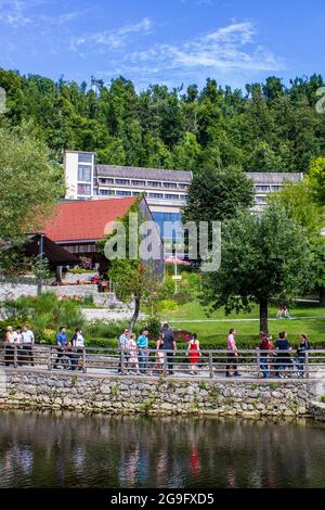 Postojna, Slowenien - 16. Juli 2017: Blick auf Touristen, die durch Postojna mit dem Hotel Jama im Hintergrund wandern Stockfoto