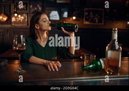 Unglückliche Frau trinkt Alkohol an der Theke in der Bar Stockfoto