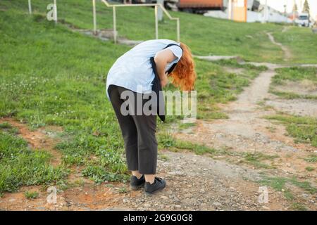 Das Mädchen beugte sich nieder, um etwas auf dem Boden zu sehen. Das Mädchen ließ eine kleine Sache fallen. Die Frau sucht Schmutz auf der Kleidung. Stockfoto