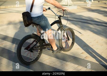 Der Typ auf dem Fahrrad. Ein Mann fährt mit dem Fahrrad um den Platz. Mieten Sie sich ein Fahrrad auf der Straße. Stockfoto