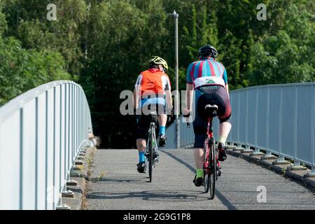 Zwei Radfahrer überqueren eine Fuß-/Radweg-Brücke, Warwickshire, Großbritannien Stockfoto