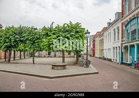 Vlisssingen, Niederlande, 24. Juli 2021: Von Bäumen gesäumter kleiner Platz und Straße mit bunten Fassaden in der Altstadt Stockfoto