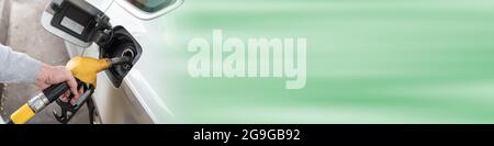 Gelbe Zapfpistole von Hand halten und Fahrzeug nachfüllen Stockfoto