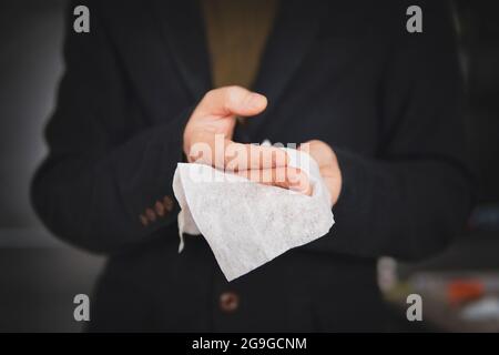 Mann, der seine Hände mit antibakterieller Sanitärserviette reinigt, nachdem er gearbeitet hat, um die Ausbreitung von Viren und Bakterien zu verhindern. Geschäftsmann desinfiziert seine Hände afte Stockfoto