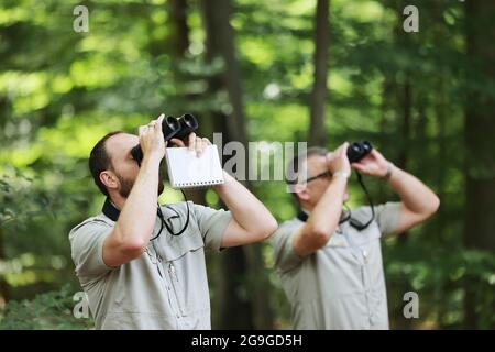 26. Juli 2021, Nordrhein-Westfalen, Rösrath: Die Förster Holger Beding (l) und Lutz Jaschke untersuchen mit einem Fernglas den Zustand von Buchen im Königsforst-Wald. Das Staatliche Forstamt hat mit der Untersuchung des Waldzustands begonnen. Foto: Oliver Berg/dpa Stockfoto