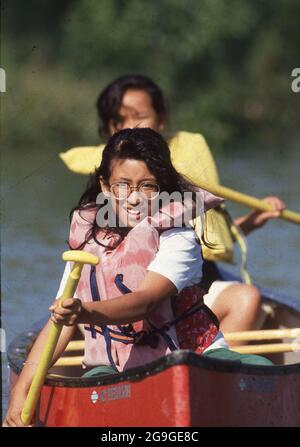 Bandera Texas USA, 1991: Mädchen der fünften Klasse, die Rettungsringe tragen, paddeln während eines nächtlichen Schulausflugs zu einem Camp im Texas Hill Country mit einem Kanu. ©Bob Daemmrich Stockfoto