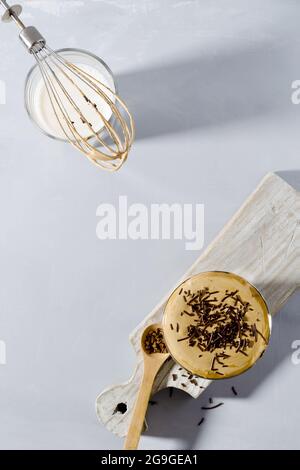 Kaffee-Dalgon in einem Glas auf einem Holzständer mit Kopierraum und einem flachen Layout auf grauem Hintergrund Stockfoto