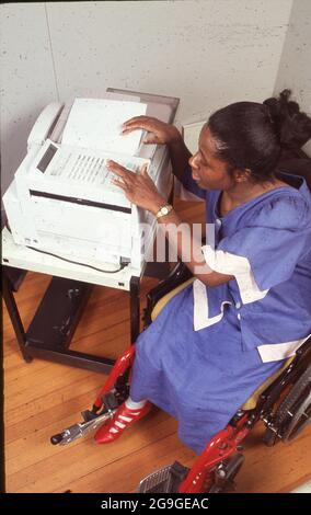 Austin, Texas USA,1993: Schwarze Geschäftsfrau im Rollstuhl benutzt ein Faxgerät. HERR ©Bob Daemmrich Stockfoto