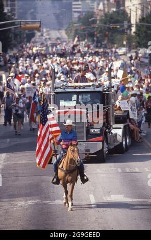 Austin Texas USA, 1993: Ein Mann auf dem Pferderücken, der eine texanische Flagge trägt, führt einen Protestierenden, der die Congress Avenue in Richtung Capitol aufmarschiert. Die Gruppe setzt sich für Steuerrechte für Privateigentum ein, die durch ein Gesetz in der aktuellen Sitzung der texanischen Legislative bedroht werden. ©Bob Daemmrich Stockfoto