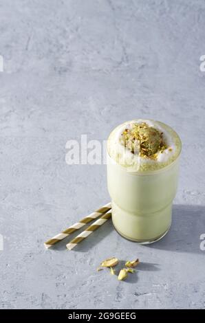 Grüner Kaffee Matcha Latte mit Schaum bestreut mit Nüssen auf einem Betonhintergrund mit Kopierraum Stockfoto