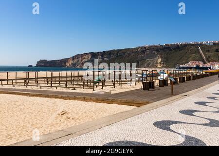 Nazare, Portugal - 28. Juni 2021: Blick auf den Strand von Nazare mit dem Leuchtturm im Hintergrund Stockfoto