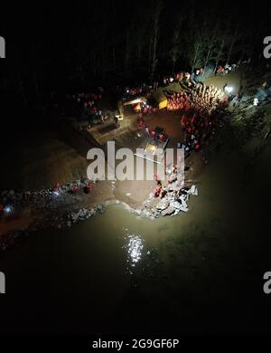 Hebi. Juli 2021. Das Luftfoto vom 26. Juli 2021 zeigt, wie Retter den Ausbruch des Damms am Fluss Weihe im Dorf Pengcun, Stadt Hebi in der zentralchinesischen Provinz Henan, blockieren. Von anhaltenden Niederschlägen betroffen, kam es im Dorfeinteil des Weihe River in Pengcun zu einem Damm-Bruch. Die Verletzung war am frühen Montagmorgen nach mehr als 70 Stunden Rettungsarbeit blockiert worden. Quelle: Feng Dapeng/Xinhua/Alamy Live News Stockfoto