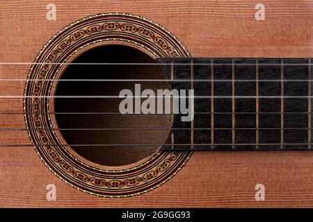 Nahaufnahme einer alten Akustikgitarre mit einem Detail aus dekorativem Rosettendekal um das Schallloch, die Saiten und einen Teil des Griffbretts aus Ebenholz. Draufsicht Stockfoto