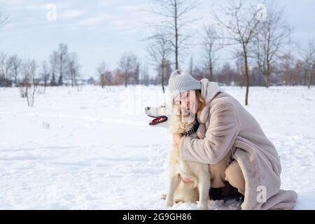 Junge schöne Frau und ihr goldener Retriever Hund haben Spaß im Winter. Stockfoto