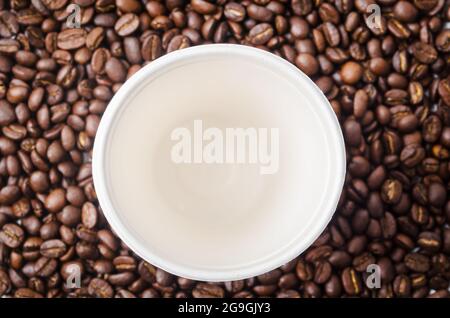 Leere Kaffeetasse aus Papier auf dem Hintergrund der Kaffeebohnen. Stockfoto
