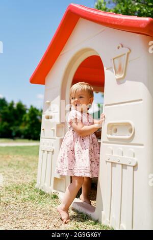 Das kleine Mädchen geht in das Spielzeughaus auf dem Spielplatz Stockfoto