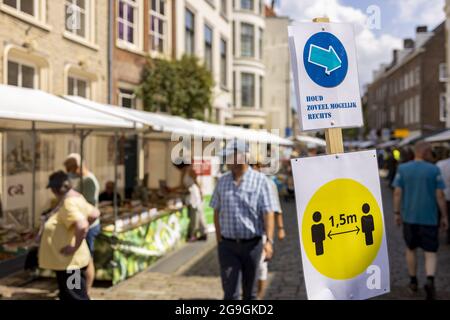 ZUTPHEN, NIEDERLANDE - 25. Jul 2021: Soziale Distanzierung und Richtungszeichen auf einer Buchmesse während der COVID-19 Pandemie an einem sonnigen Tag. Stockfoto