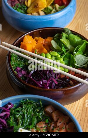 Vegane Schüssel mit Kürbis, Reis, Wakame, Edamame, Rotkohl und Lammsalat in einer Schüssel. Hawaiianische Poke-Schale. Stockfoto