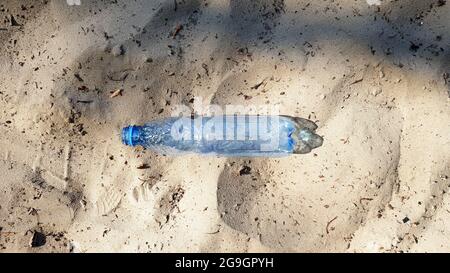 Die Flasche ist aus Kunststoff. Ökologie, Plastikverschmutzung. Meeresverschmutzung. Plastik im Sand. Müll am Strand Konzept. Künstliche Verschmutzung und Poster. Stockfoto