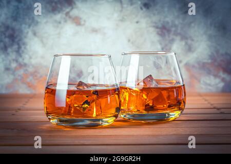 Zwei Gläser Whisky mit Eis. Stillleben. Brandy, Bourbon auf einem braunen Holztisch. Starker Alkoholkonsum. Rum, Scotch Stockfoto