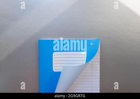 Designkonzept - Draufsicht einer hochwertigen männlichen Hand, die durch ein Blatt blau gestreiftes Notizbuch blättert. Draufsicht, Kopierbereich, flach liegend. Stockfoto