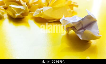 Ball zerknittert Papierkugel isoliert auf einem gelben Hintergrund. Zerknittertes Papier für Textur. Zerknittertes Papier nach einem Brainstorming wurde in den Papierkorb geworfen. A Stockfoto