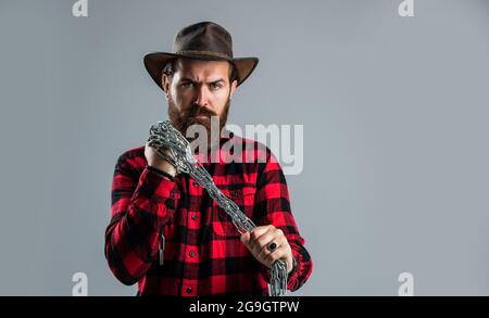 Brutaler Cowboymann mit Bart und Schnurrbart, Stahlkette ziehen, Trap-Konzept Stockfoto