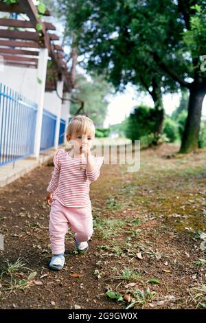 Nachdenkliche Kinder gehen den Weg entlang, vorbei am Zaun in der Nähe des Hauses Stockfoto