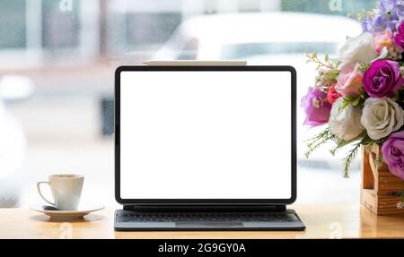 Digitales Tablet mit leerem weißen Bildschirm am Arbeitsplatz im Café Stockfoto