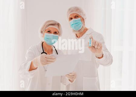 Ärzte mit Maske zeigen den Covid-19-Virus-Impfstoff Stockfoto