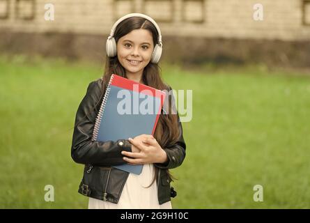 Mädchen hören Audio tragen Lehrbücher auf dem Weg zur Schule, Sprachunterricht Konzept Stockfoto
