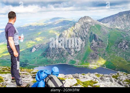 Snowdonia, Großbritannien. Juli 2021. Die Berge des Snowdonia National Park in Nordwales bieten spektakuläre, atemberaubende Aussichten für diejenigen, die einen Abenteuerurlaub verbringen möchten. Ein Wanderer wird hier gezeigt, nachdem er den Gipfel von Pen yr Ole Wen erreicht hat und die herrliche Aussicht genießt, während er in das Tal hinunter zum Ogwen-See und hinüber zum Berg Tryfan blickt. Kredit: Lee Hudson Stockfoto