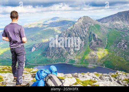 Snowdonia, Großbritannien. Juli 2021. Die Berge des Snowdonia National Park in Nordwales bieten spektakuläre, atemberaubende Aussichten für diejenigen, die einen Abenteuerurlaub verbringen möchten. Ein Wanderer wird hier gezeigt, nachdem er den Gipfel von Pen yr Ole Wen erreicht hat und die herrliche Aussicht genießt, während er in das Tal hinunter zum Ogwen-See und hinüber zum Berg Tryfan blickt. Kredit: Lee Hudson Stockfoto