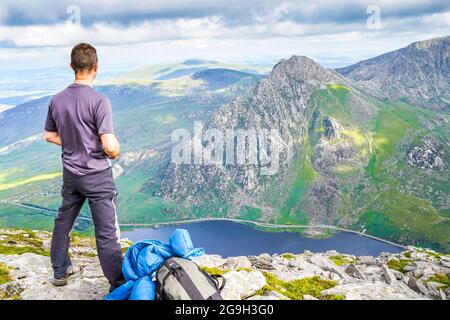 Snowdonia, Großbritannien. Juli 2021. Die Berge des Snowdonia National Park in Nordwales bieten spektakuläre, atemberaubende Aussichten für diejenigen, die einen Abenteuerurlaub verbringen möchten. Ein Wanderer wird hier gezeigt, nachdem er den Gipfel von Pen yr Ole Wen erreicht hat und die herrliche Aussicht genießt, während er in das Tal hinunter zum Ogwen-See und hinüber zum Berg Tryfan blickt. Kredit: Lee Hudson Stockfoto