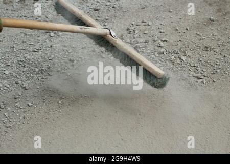 Der Mopp entfernt Staub und Sand von der Straße. Außenreinigungsreiniger. Ein Wischmopp mit festen Borsten und einem Griff aus Holz. Stockfoto