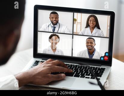 African American Male Doctor Bei Laptop Machen Video Call Beratung Mit Kollegen Gruppe Sitzen Im Büro. Distanz Online Medical Conference Concep Stockfoto